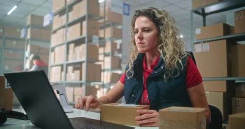 Female Manager Scans Parcel Using Barcode Scanner Enters Data on Laptop