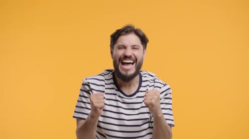 Excited Man Celebrates Success on Orange Background