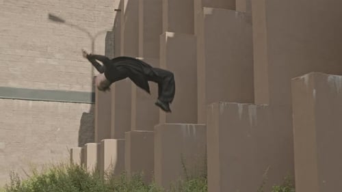 Man Doing Backflip off Concrete Plate Outdoors