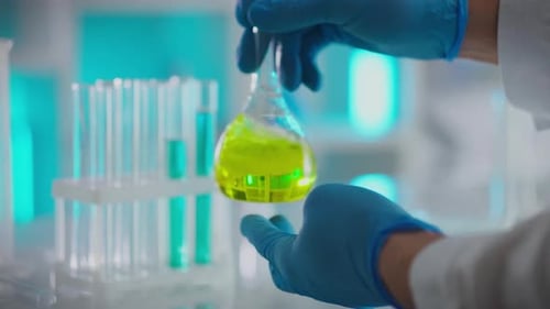 Scientist Holding Flask with Yellow Liquid in Lab
