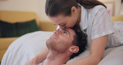 Loving Woman Kisses Man on Forehead on Bed