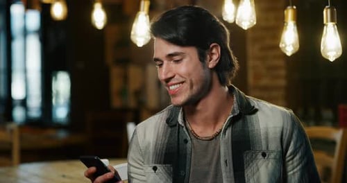 Smiling Man Using Phone in Cafe