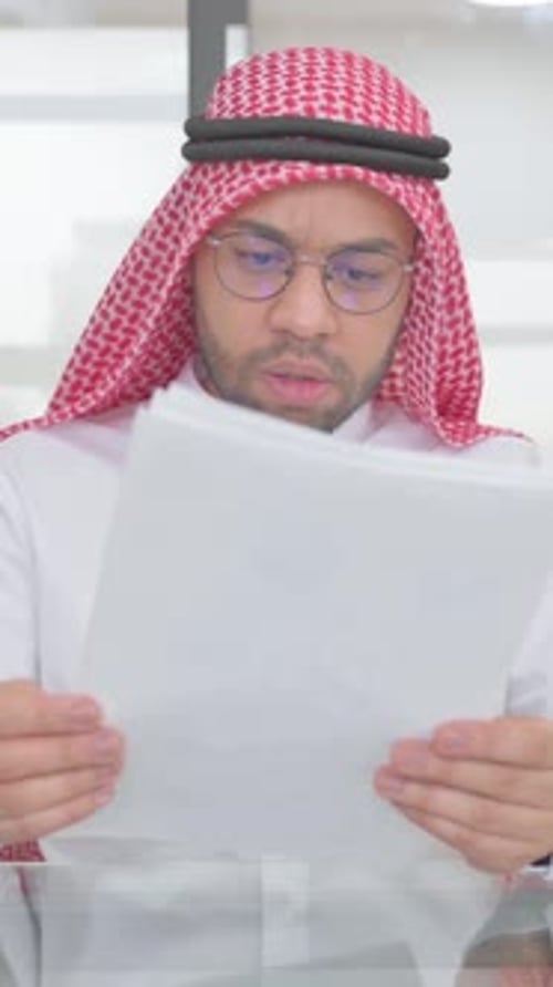 Man in Keffiyeh Reviews Documents with Frustration