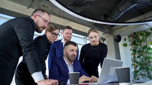 Happy business people looking at laptop presentation, success at work, sitting in modern office.