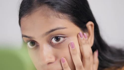 A woman checking her under eye dark circle in mirror