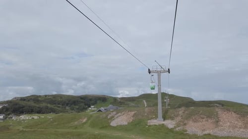 Passing green cable car gondola sightseeing transportation moving up scenic mountain valley hillside