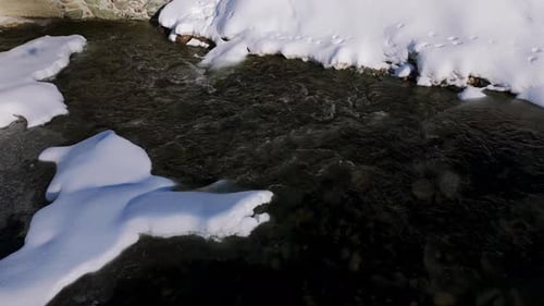 Snow and ice on rock in freezing water stream. Aerial drone view