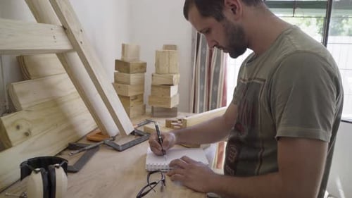 Man Drawing Construction Sketch at Workshop Desk