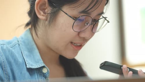 Asian student doing research in library using laptop books making a project and preparing for exam.