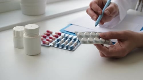 Doctor is Pointing to Drug Tablets and Giving Medicine to Female Patient at Office