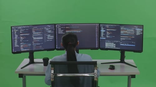 Rückansicht einer müden Frau, die sich beim Schreiben von Code mit mehreren Bildschirmen auf grünem Bildschirm dehnt