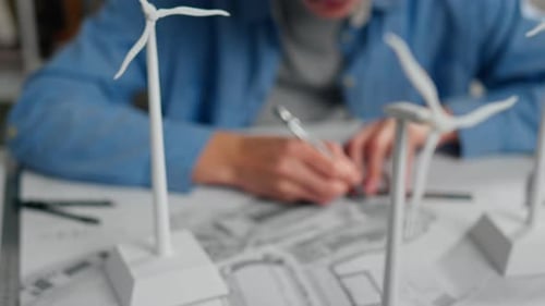 Designer working on a wind turbine model in a creative workspace during daylight hours