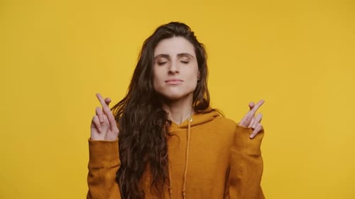 Hopeful Woman Crossing Fingers on Yellow