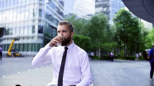 Hipster Businessman Sitting in the City, Drinking Coffee and Checking the Time