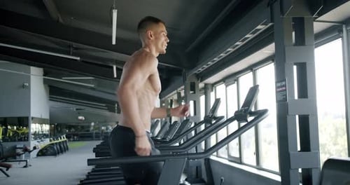 Active Athlete Male Exercising and Running on Treadmill at Gym