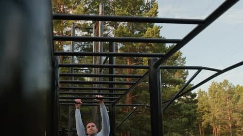 Man Hopping Onto and Going Across Monkey Bars in Outdoor Gym