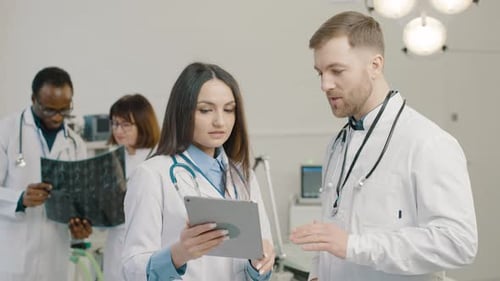 Medical Team Discussing Data on Tablet in Hospital