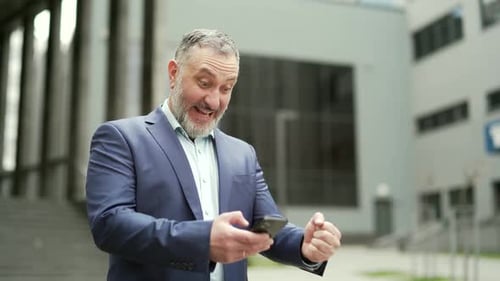 Successful senior investor with mobile phone outside office building Middle-aged businessman