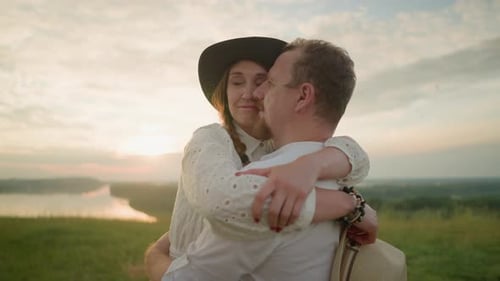 Husband and Wife Tenderly Embrace at Sunset in a Grassy Field