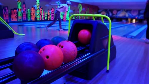 Bowling ball return. Close-up of colorful bowling balls resting in the ball return at a neon-lit bow