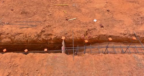 Trabalhando em um canteiro de obras para instalar aço em uma trincheira a fim de construir uma base de casa
