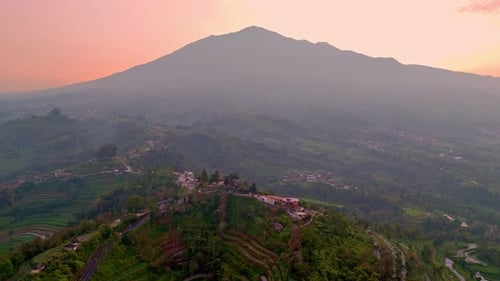 Aerial view of highland with view of reddish sunrise sky and Merbabu Mountain. Beautiful scenery of