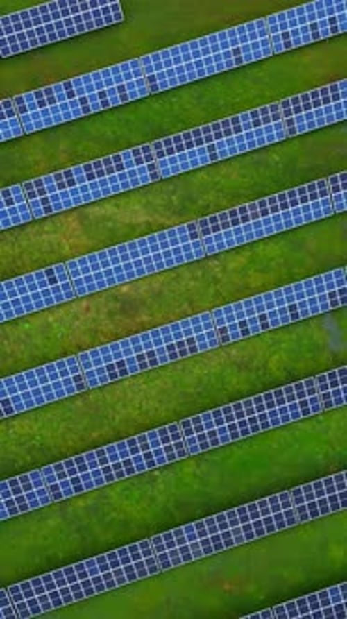 Drohnenaufnahme von oben nach unten von langen parallelen Reihen von Solarmodulen, die klare geometrische Linien auf einem hellen