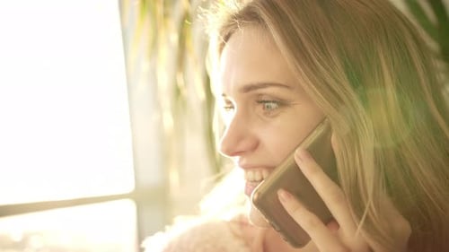Cheerful woman talking on phone indoors during daytime