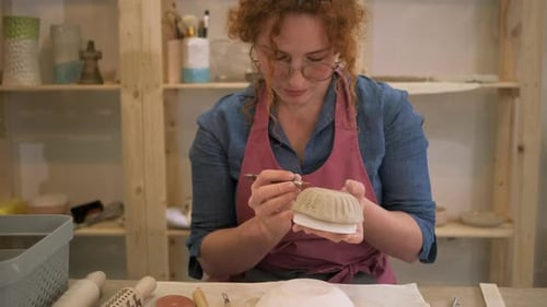 Woman working in pottery studio workshop making bowl from clay.