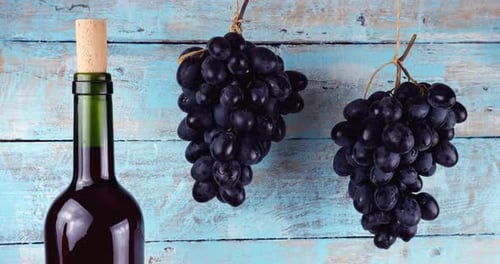 Grapes and wine bottle on blue vintage wooden background.