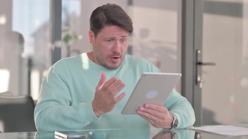 Man At Table Using Tablet Reacts To Content