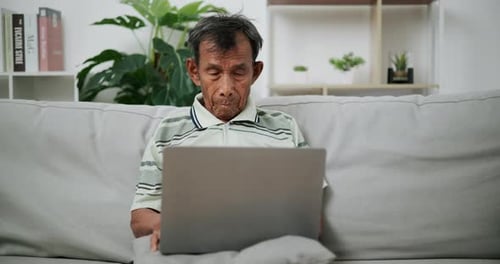 Senior Man Relaxing on Couch Using Laptop