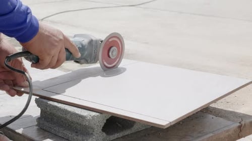 Adult Cutting Gray Tile With Circular Saw