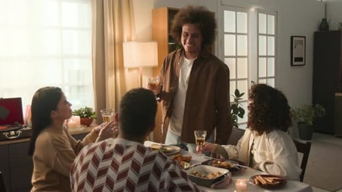 Four Smiling Friends Raising Glasses in Toast Amidst Sunlit Room, Enjoying Meal