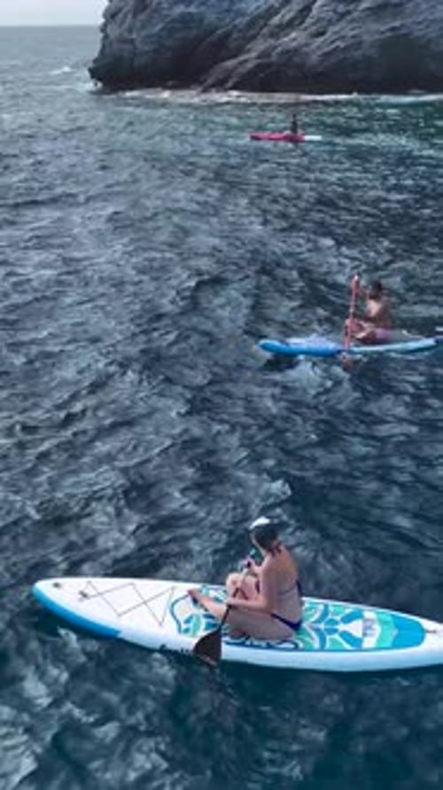 Vertical Video People Paddle on SUP Boards in the Open Sea Relaxing Over CrystalClear Azure Waters