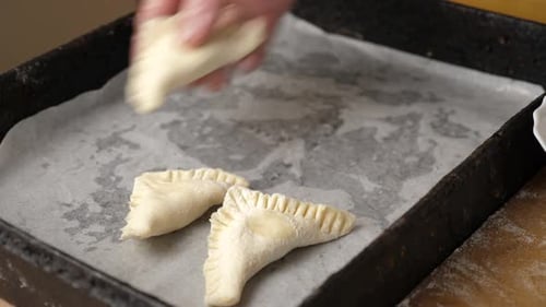 22, Les tartes à cuire sont disposées sur une plaque à pâtisserie recouverte de parchemin. Faire cuire des tartes.