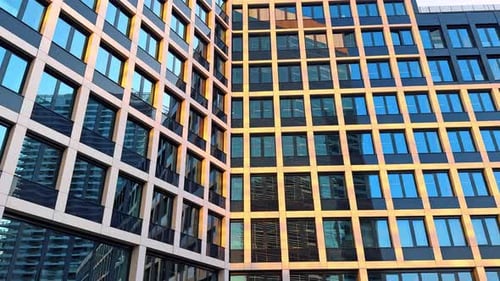 Modern facade of the high-rise multi-storied building. Neighboring building reflects in the windows.