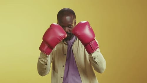Man Poses in Boxing Gloves on Yellow Background