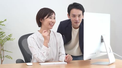 Two asian businesspeople working together in the office while using laptop