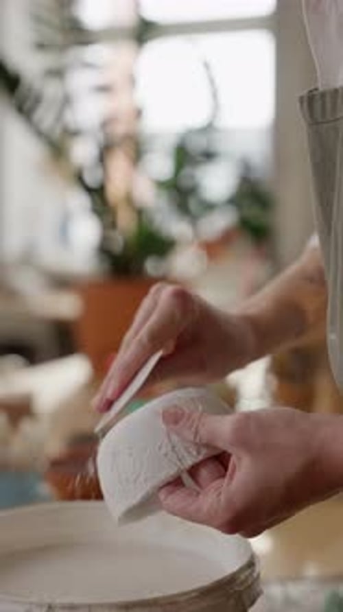 Hands trim clay from a ceramic bowl