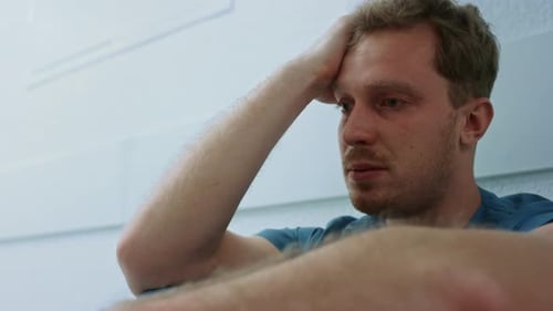Cirujano molesto mirando hacia adelante sentado de cerca en el piso de la clínica. Cansado, exceso de trabajo