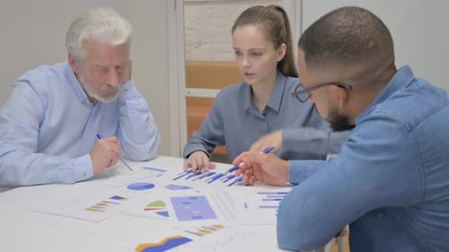Coworkers Discussing Charts at Workplace Meeting