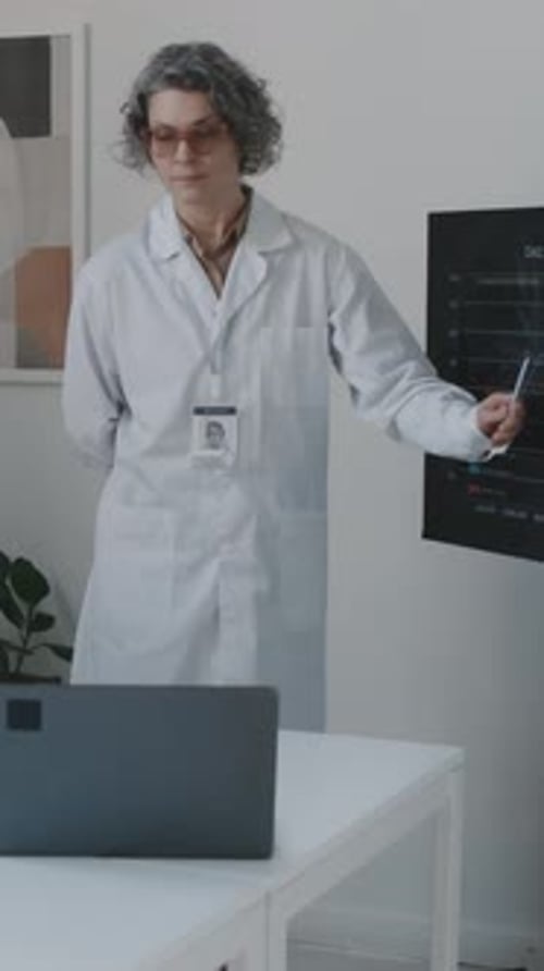 Female Medical Director Reporting at Staff Meeting and Answering Questions