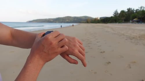 A Closeup of Turning on the Tracker on a Smart Watch and Starting a Workout on the Beach