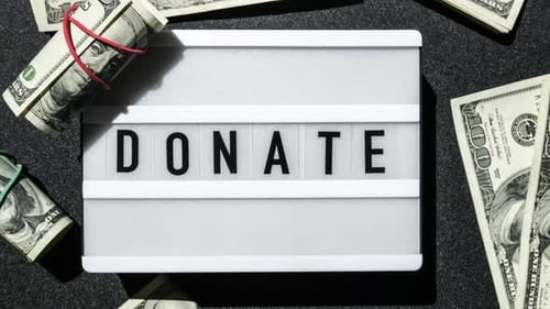 Zoom in Out Lightbox Board with Word DONATE in Black Letters Around US Dollar Banknotes