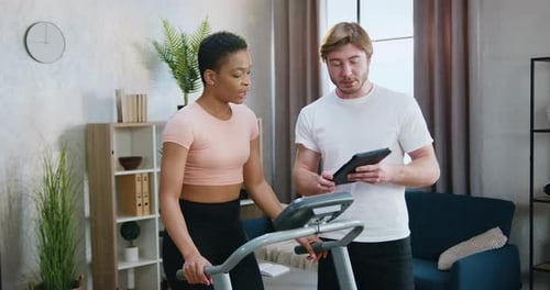 Woman Exercises on Treadmill with Tablet Guidance