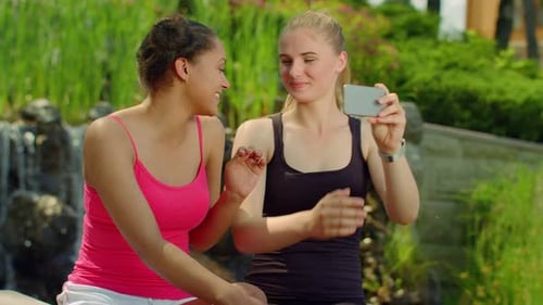 Glückliche Freundinnen beim Fotografieren mit Smartphone im Park. Multiethnische Mädchen haben