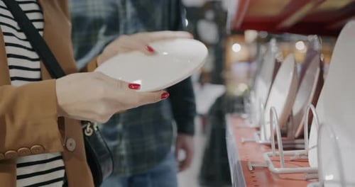 Woman Examines White Plates in Store