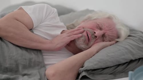 Senior Man in Bed with Tooth Pain