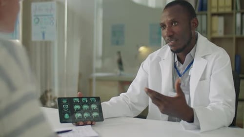 Black Doctor Showing CT Scan on Tablet to Patient